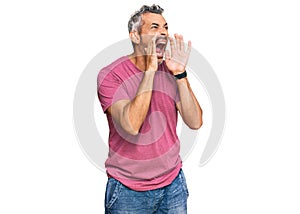 Middle age grey-haired man wearing casual clothes shouting angry out loud with hands over mouth