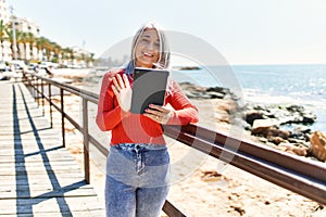 Middle age grey-haired woman having video call using touchpad at the beach