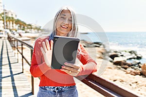 Middle age grey-haired woman having video call using touchpad at the beach