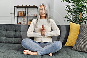 Middle age grey-haired woman smiling confident doing yoga exercise at home