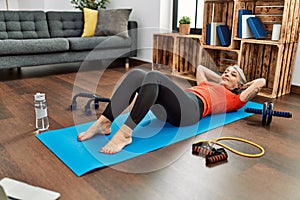 Middle age grey-haired woman smiling confident training abs exercise at home