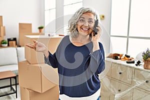 Middle age grey-haired woman talking on the smartphone moving at new home