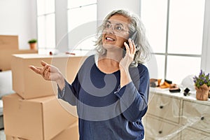 Middle age grey-haired woman talking on the smartphone moving at new home