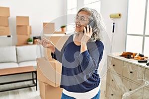 Middle age grey-haired woman talking on the smartphone moving at new home