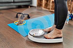 Middle age grey-haired woman using weighing machine at home