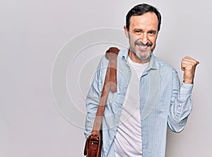 Middle age handsome businessman wearing leather bag over isolated white background pointing thumb up to the side smiling happy