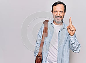 Middle age handsome businessman wearing leather bag over isolated white background smiling with an idea or question pointing
