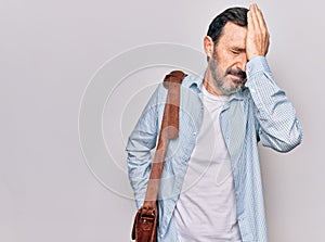 Middle age handsome businessman wearing leather bag over isolated white background surprised with hand on head for mistake,