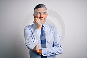 Middle age handsome grey-haired business man wearing elegant shirt and tie looking stressed and nervous with hands on mouth biting