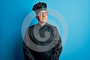 Middle age handsome grey-haired chef man wearing cooker uniform and hat smiling looking to the side and staring away thinking