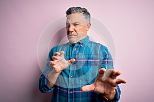 Middle age handsome grey-haired man wearing casual shirt over isolated pink background disgusted expression, displeased and