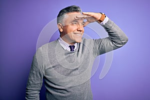 Middle age handsome grey-haired man wearing elegant sweater over purple background very happy and smiling looking far away with