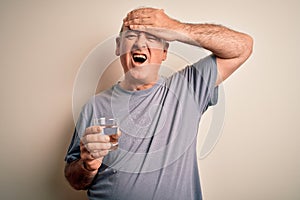 Middle age handsome hoary man drinking glass of water over isolated white background stressed with hand on head, shocked with