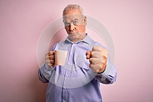 Middle age handsome hoary man drinking mug of coffee over isolated pink background annoyed and frustrated shouting with anger,