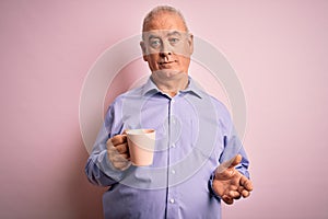 Middle age handsome hoary man drinking mug of coffee over isolated pink background with a confident expression on smart face