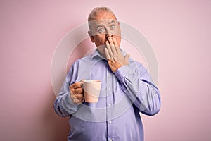 Middle age handsome hoary man drinking mug of coffee over isolated pink background cover mouth with hand shocked with shame for