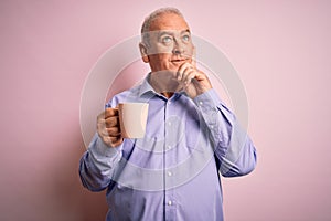 Middle age handsome hoary man drinking mug of coffee over isolated pink background serious face thinking about question, very