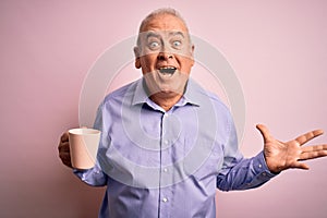 Middle age handsome hoary man drinking mug of coffee over isolated pink background very happy and excited, winner expression