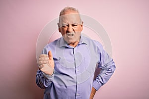 Middle age handsome hoary man wearing casual shirt standing over pink background angry and mad raising fist frustrated and furious