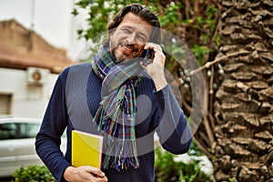 Middle age handsome man speaking on the phone outdoors at the park