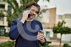 Middle age handsome man speaking on the phone outdoors at the park