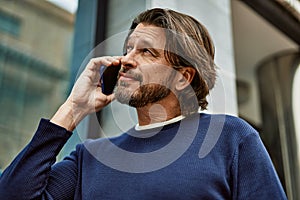 Middle age handsome man speaking on the phone at the town