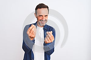 Middle age handsome man wearing blue denim shirt standing over isolated white background doing money gesture with hands, asking