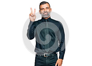 Middle age handsome man wearing business clothes smiling with happy face winking at the camera doing victory sign