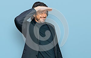 Middle age handsome man wearing business clothes very happy and smiling looking far away with hand over head