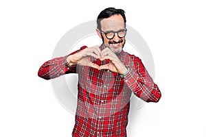 Middle age handsome man wearing casual shirt and glasses over isolated white background smiling in love doing heart symbol shape