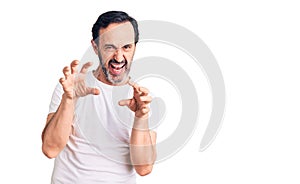 Middle age handsome man wearing casual t-shirt smiling funny doing claw gesture as cat, aggressive and sexy expression