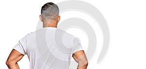 Middle age handsome man wearing casual white tshirt standing backwards looking away with arms on body