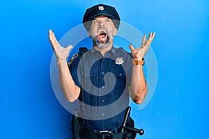 Middle age handsome man wearing police uniform crazy and mad shouting and yelling with aggressive expression and arms raised