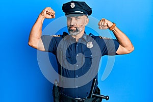 Middle age handsome man wearing police uniform showing arms muscles smiling proud