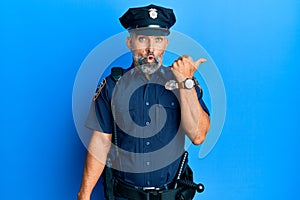 Middle age handsome man wearing police uniform surprised pointing with hand finger to the side, open mouth amazed expression
