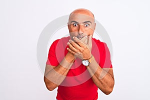 Middle age handsome man wearing red casual t-shirt standing over isolated white background shocked covering mouth with hands for