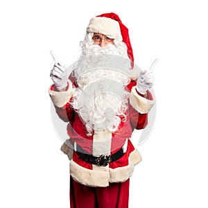 Middle age handsome man wearing Santa Claus costume and beard standing smiling confident pointing with fingers to different