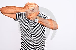 Middle age handsome man wearing striped navy t-shirt over isolated white background Covering eyes and mouth with hands, surprised