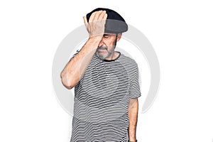 Middle age handsome man wearing striped t-shirt and french beret over white background surprised with hand on head for mistake,