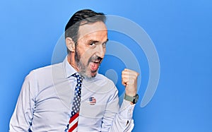 Middle age handsome patriotic businessman wearing united states tie over blue background pointing thumb up to the side smiling