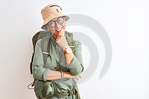Middle age hiker woman wearing backpack canteen hat glasses over isolated white background looking confident at the camera smiling