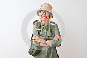 Middle age hiker woman wearing backpack hat canteen glasses over isolated white background happy face smiling with crossed arms