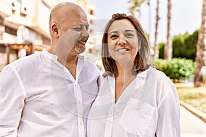 Middle age hispanic couple of husband and wife together on a sunny day outdoors