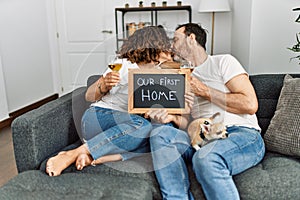 Middle age hispanic couple kissing and toasting with champagne