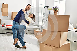 Middle age hispanic couple smiling happy and dancing at new home