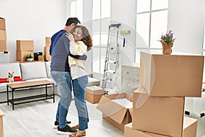 Middle age hispanic couple smiling happy and dancing at new home