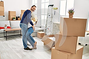 Middle age hispanic couple smiling happy and dancing at new home