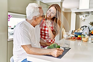 Middle age hispanic couple smiling happy eating beef with salad at the kitchen