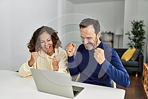 Middle age hispanic couple smiling happy with fists raised up