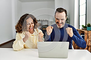 Middle age hispanic couple smiling happy with fists raised up